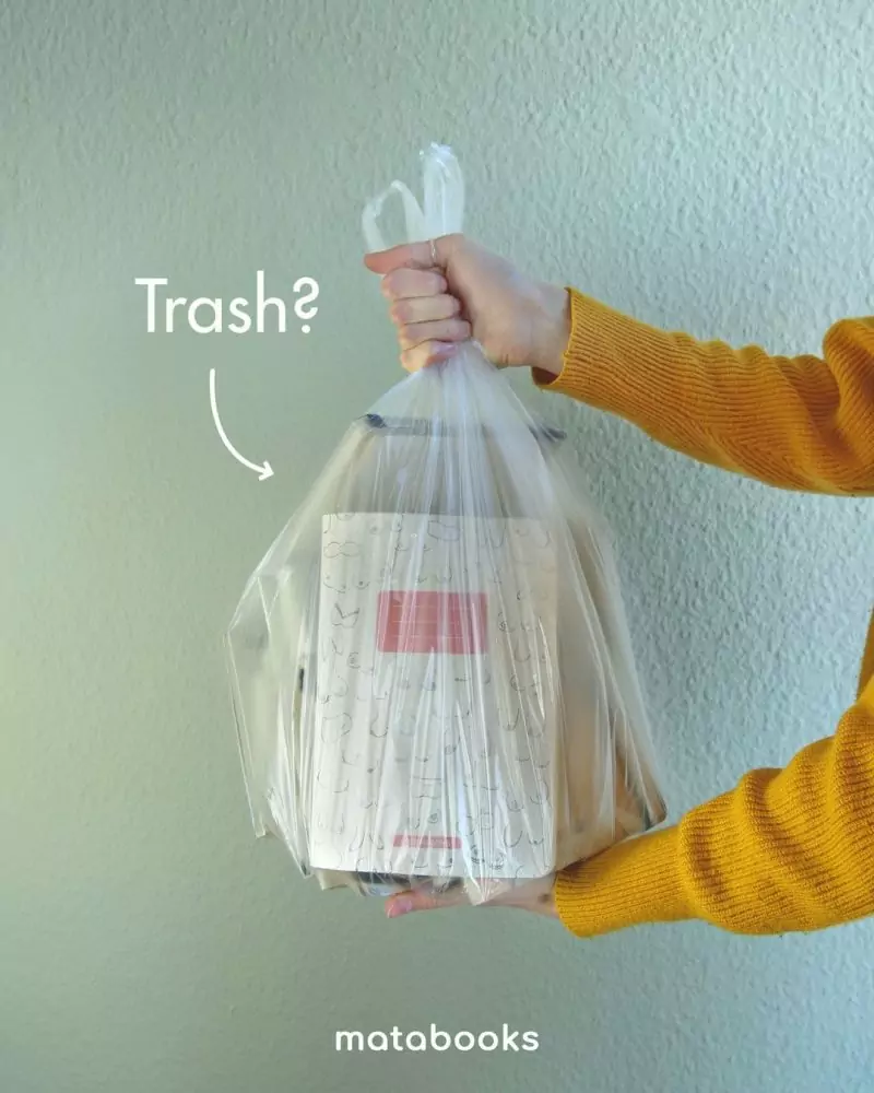 Hand hält Mülltüte mit Matabooks Notizbüchern aus Graspapier